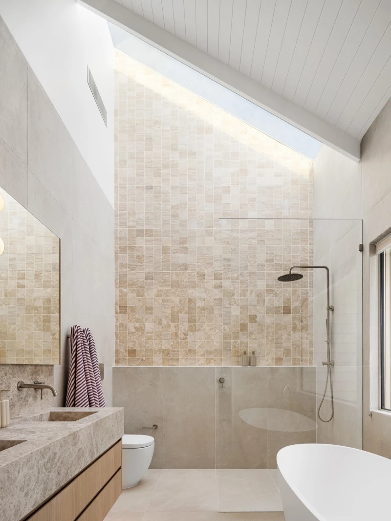 Sloped Skylight Ceiling with Travertine Mosaic Wall and Integrated Stone Sink