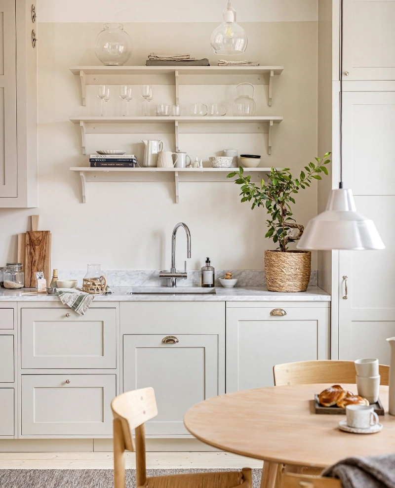 White Open Shelves with Clear Glassware, Cream Ceramics, and a Woven Potted Tree