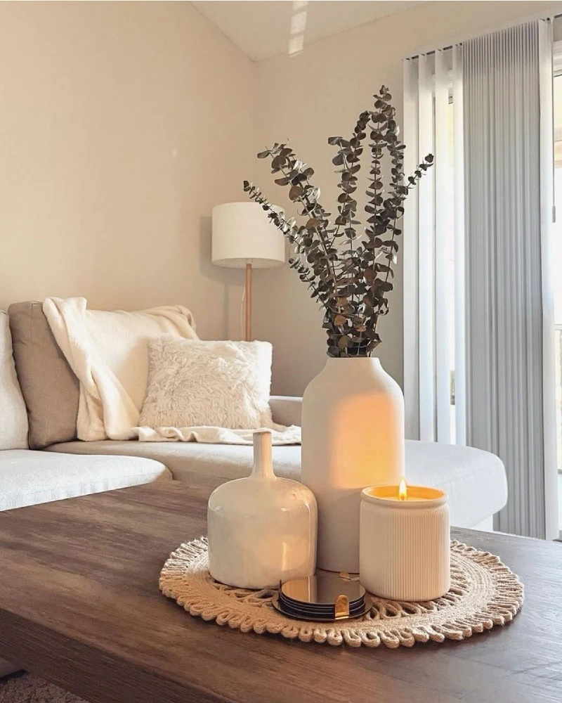 Woven Jute Mat with Ceramic Vases and Lit Candle on Wooden Coffee Table